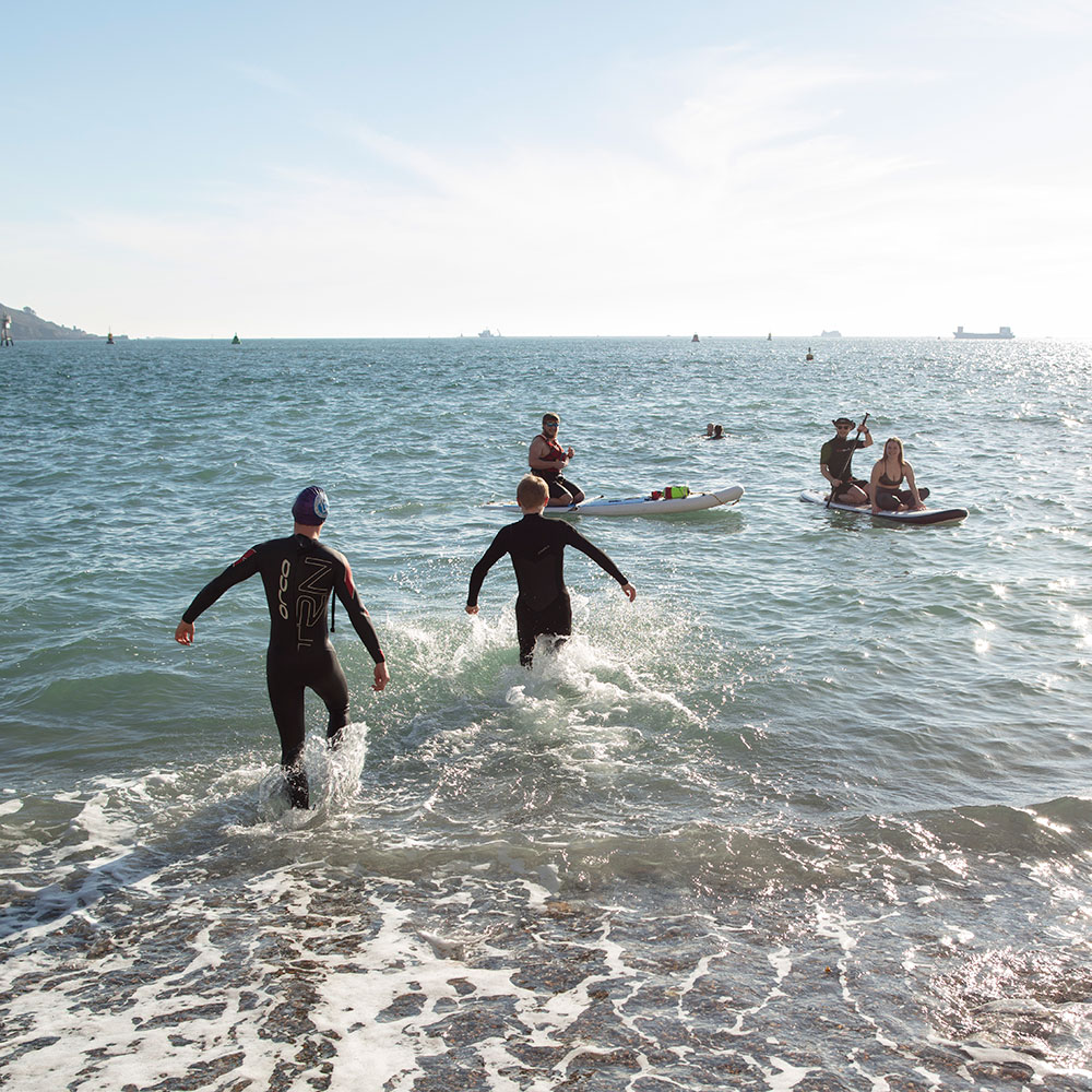 People in wetsuit and paddle boarding in Plymouth sound