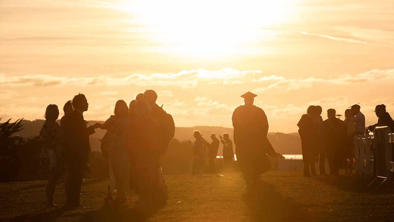 Alumni celebrating on the Hoe at sunset.