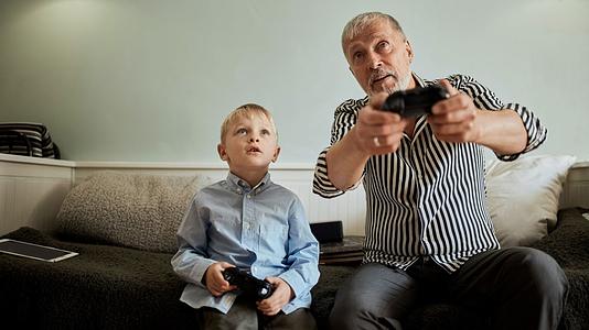 Older man playing video games with a young boy