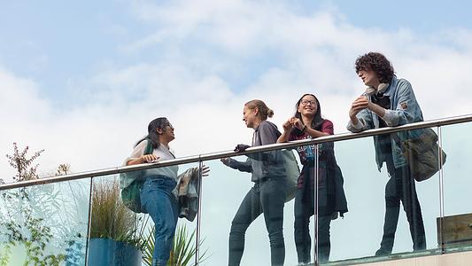 Four students leaning on a balcony
