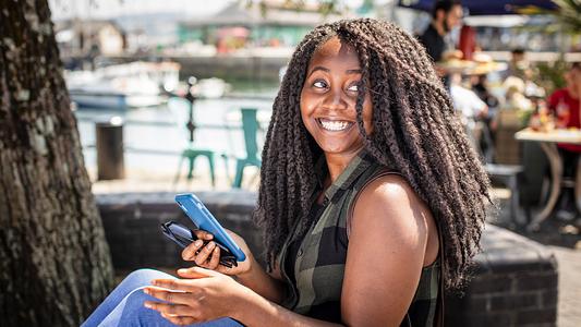 International student on the Barbican, smiling in the sunshine.