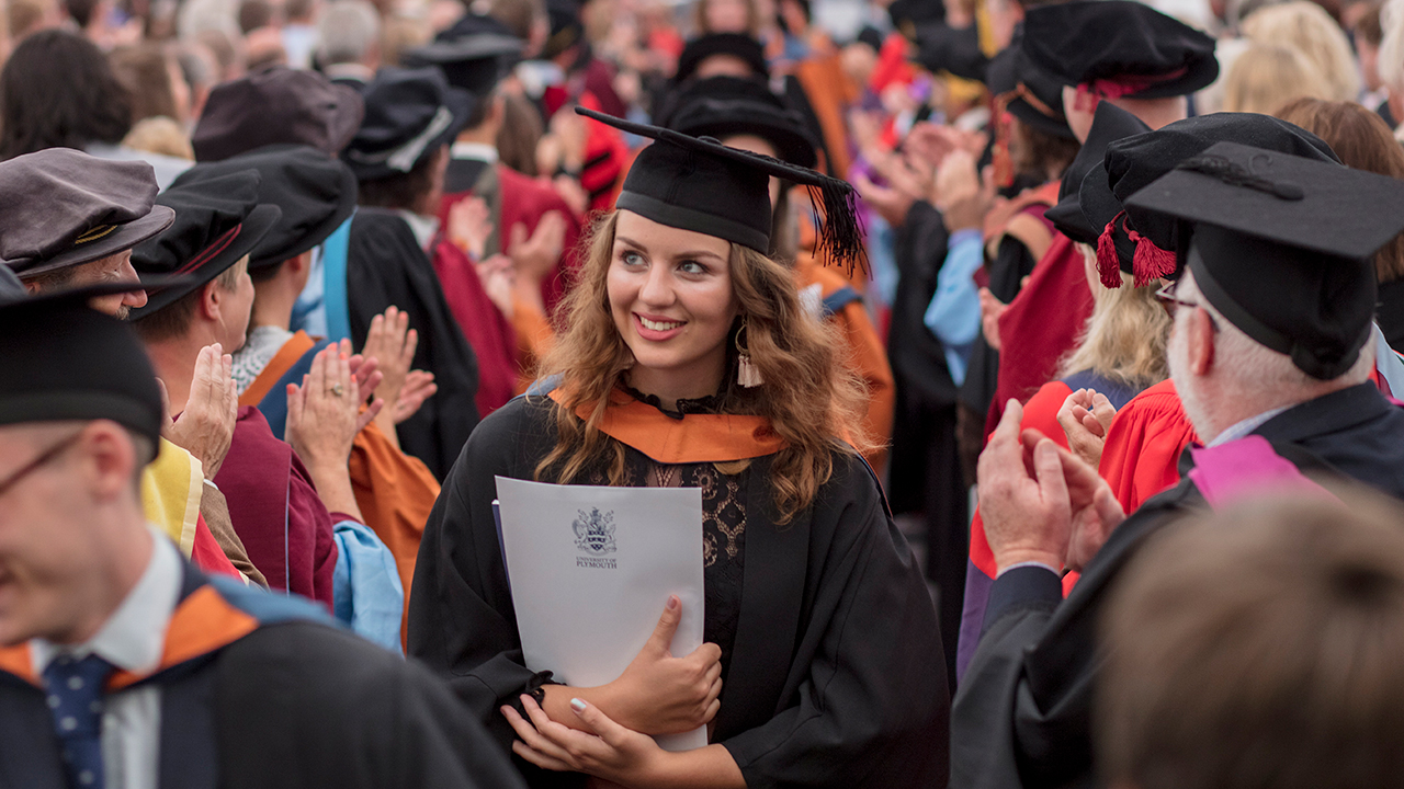 Girl walking through crowd at graduation ceremony