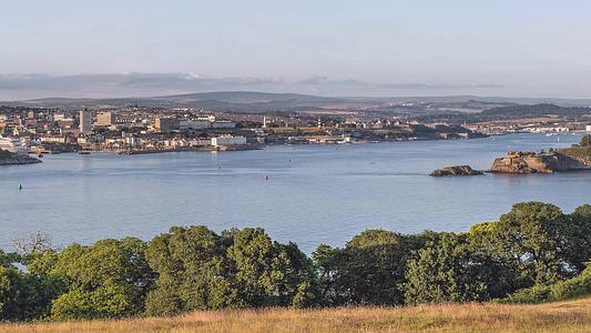 Plymouth Sound with Mount Edgcumbe in the foreground, Drake's Island in the middle ground, and the city and Dartmoor in the background